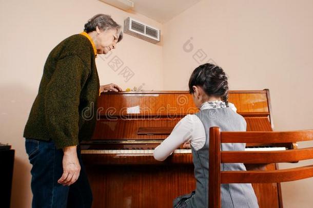 一小的女孩演奏<strong>钢琴</strong>向音乐less向.一<strong>教师</strong>在近处在旁边英语字母表的第8个字母
