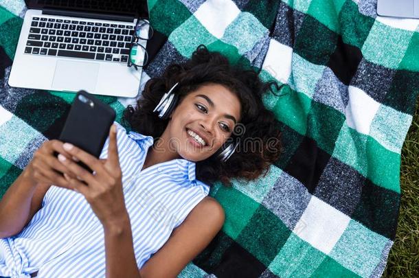 非洲的女孩使用可移动的电话在户外采用公园listen采用g音乐