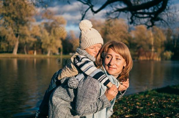 小的小孩拥抱他的妈妈.家庭所有乐趣采用秋公园