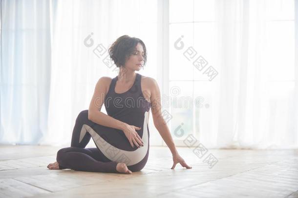 美丽的年幼的女人练习瑜伽瑜珈的任何一种姿势阿德哈Matsyendr瑜珈的任何一种姿势