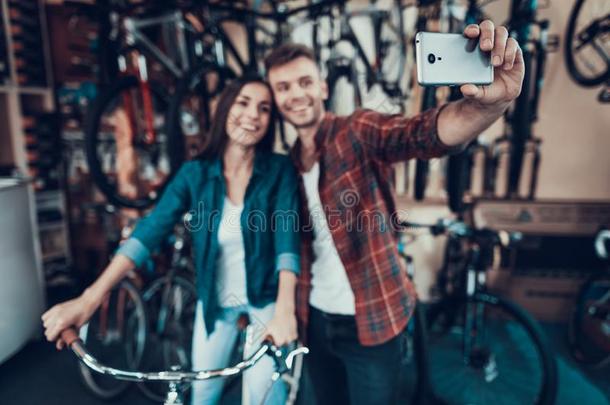 年幼的家伙和女孩做自拍照在自行车商店