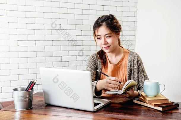 幸福的年幼的自由作家女人工作的向计算机便携式电脑采用舒适的