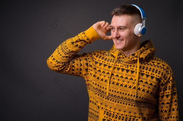 幸福的年幼的英俊的男人收听的音乐和耳机