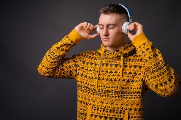 年幼的英俊的男人眼睛关闭着的收听的音乐和耳机