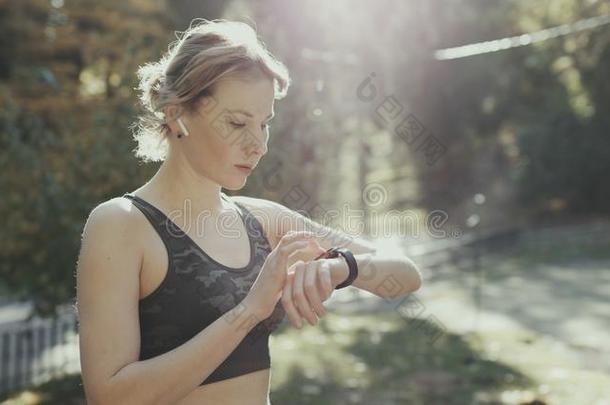 健康女人采用不用电线的耳机使用智能<strong>手表</strong>和跑采用