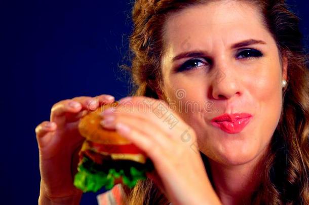 女人咬汉堡包和使眼色.幸福的学<strong>生吃</strong>s和wich午餐.