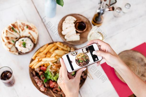 女人迷人的照片关于混合烧烤盘使用智能手机采用餐馆