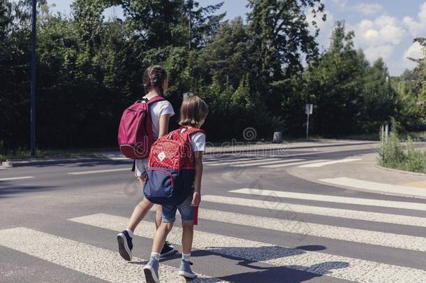 男孩和女孩和背包步行向步行者人行横道