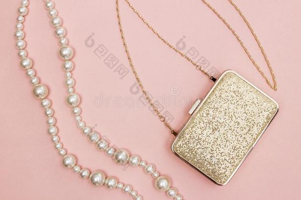 金色的钱包和珍珠项链向粉红色的背景