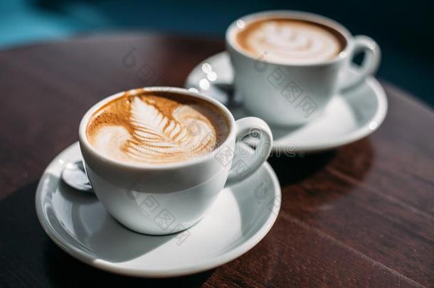 两个杯子关于卡普契诺咖啡和拿铁咖啡艺术向木制的表
