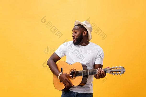 肌肉的黑的男人演奏吉他,使人疲乏的牛仔裤和白色的油箱-
