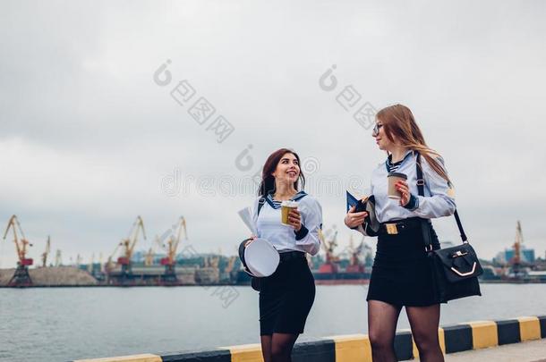 两个大学女人学生关于海的专科学校步行在旁边海穿着