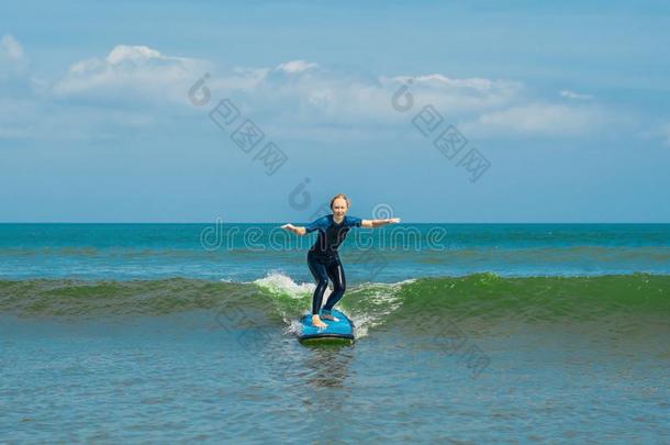 快乐的年幼的女人新手冲浪运动员和蓝色海浪有乐趣向subjectmatterarea主题区