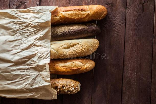 各种各样的烘烤制作的各种面包和法国长面包向乡村的木制的表.关