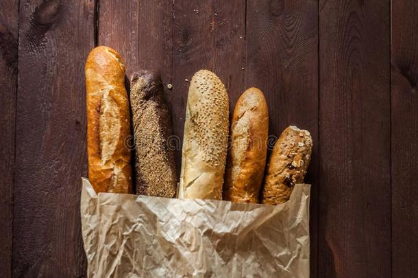 各种各样的烘烤制作的各种面包和法国长面包向乡村的木制的表.关