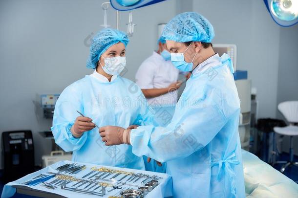镇定的护士有样子的在指已提到的人外科医生和礼物医学的器具