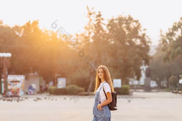 有魅力的漂亮的女孩和公文包走向大街在早晨