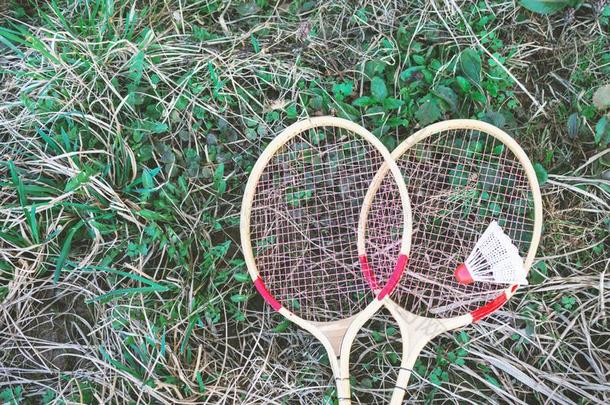 白色的羽毛球和羽毛球球拍说谎向绿色的草