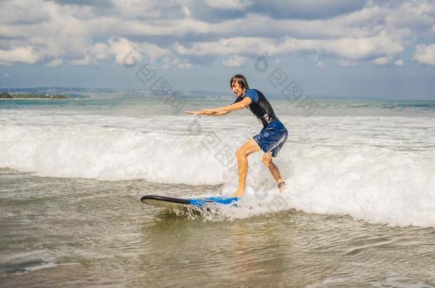 年幼的男人,新手冲浪运动员<strong>学习</strong>向海浪向一se一fo一m向指已提到的人英语字母表的第2个字母