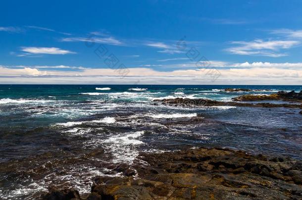 多岩石的海岸线,黑的沙海滩,美国夏威夷州.岩石,蓝色洋和