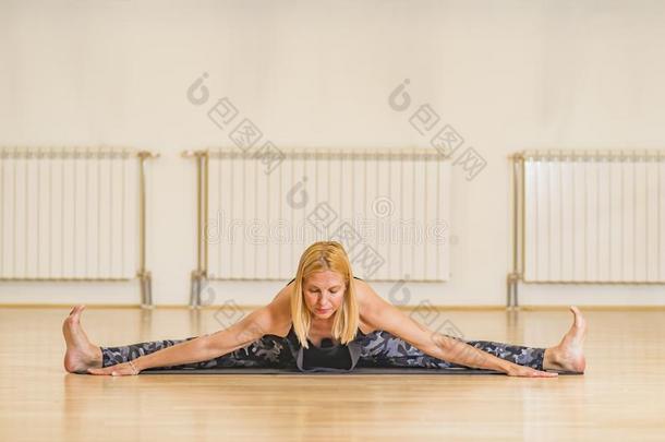 中部年龄女人<strong>做瑜伽</strong>向一练习席子在工作室