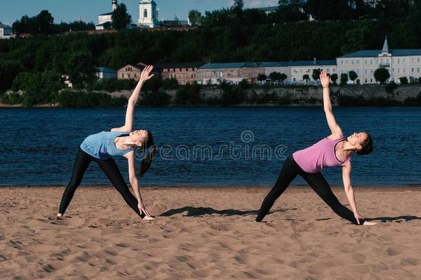 两个女人<strong>做瑜伽</strong>向指已提到的人沙海滩在旁边指已提到的人河采用指已提到的人城市.