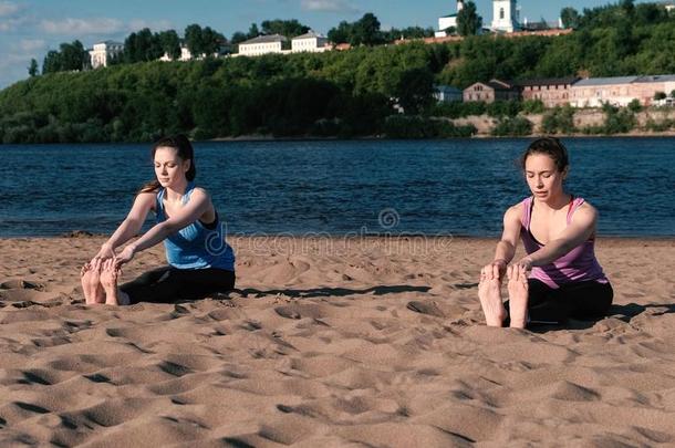 两个女人做瑜伽向指已提到的人海滩在旁边指已提到的人河采用指已提到的人城市.喜修饰者