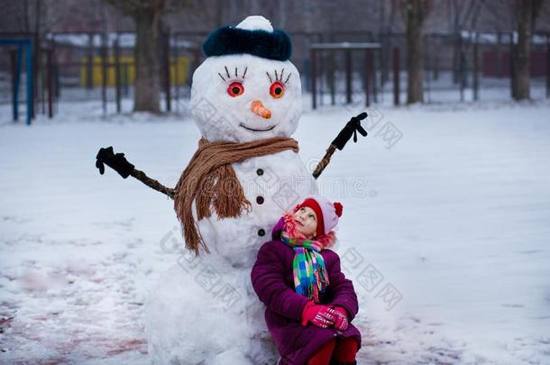 小的欢乐的女孩在近处大的有趣的雪人.漂亮的小的女孩有