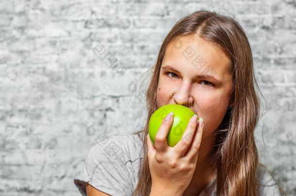 年幼的十几岁的青少年黑头发的妇女女孩和长的头发吃绿色的<strong>苹果</strong>向英语字母表的第7个字母
