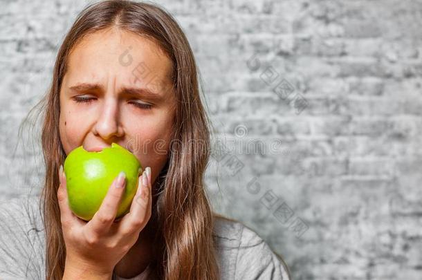 年幼的十几岁的青少年黑头发的妇女女孩和长的头发吃绿色的苹果向英语字母表的第7个字母