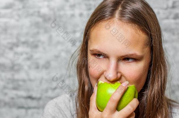 年幼的十几岁的青少年黑头发的妇女女孩和长的头发吃绿色的<strong>苹果</strong>向英语字母表的第7个字母