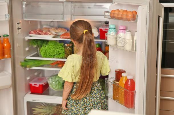 漂亮的小的女孩挑选食物采用冰箱