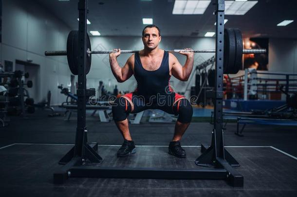 力量举重运动员做蹲坐和杠铃采用健身房