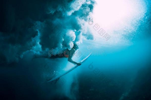 冲浪运动员女人和冲浪板潜水在<strong>水中</strong>的和在下面大的<strong>波浪</strong>.