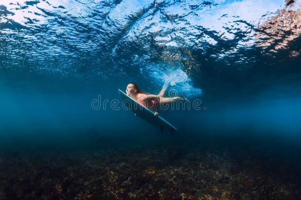 像运动家的冲浪运动员女人潜水在水中的和在下面波浪.