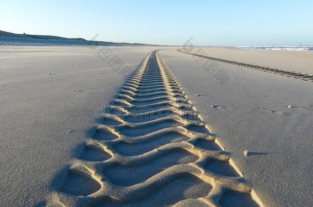 使疲惫小路向光滑的沙的无人居住的海滩