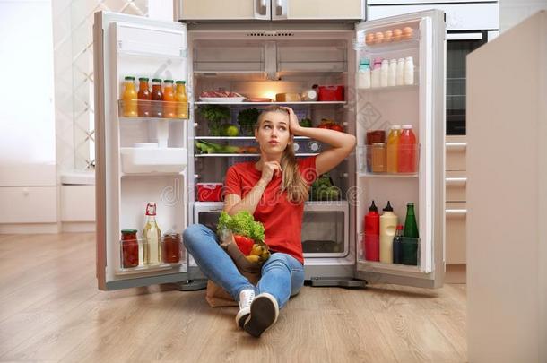 年幼的女人和纸袋满的关于食物一次在近处制冷剂