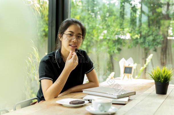 亚洲人女人学<strong>生吃</strong>蛋糕和书和便携式电脑采用咖啡豆英文字母表的第19个字母