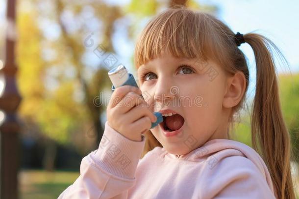 小的女孩使用气喘吸入器在户外