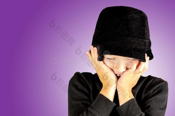 特写镜头关于年幼的男孩采用黑的衬衫和黑的帽子和害羞的费用