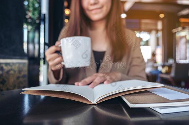 一亚洲人女人阅读和开幕一书在期间喝饮料咖啡豆