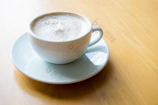 热的咖啡豆卡普契诺咖啡杯子和奶起泡沫向木材表后座
