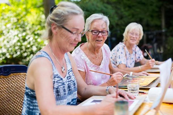 退休的较高的女人绘画同时在户外同样地组重新治疗