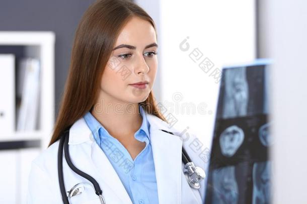 医生女人仔细检查字母x-射线照片在期间起立在近处窗