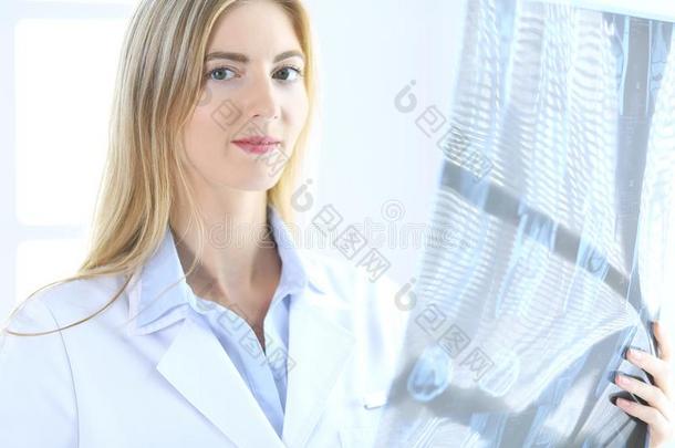 医生女人骨科医生仔细检查字母x-射线照片在期间起立