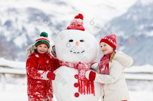 小孩建筑物雪人.小孩建造雪男人.男孩和女孩佩林