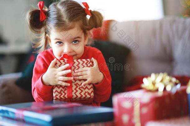 幸福的小孩女孩和圣诞节礼物在近处圣诞节树采用粗腐殖质