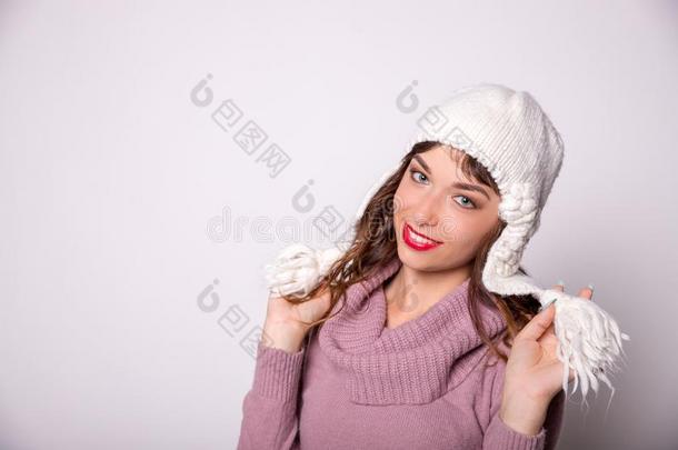 女人使人疲乏的暖和的冬衣服和针织品帽子.微笑的女孩