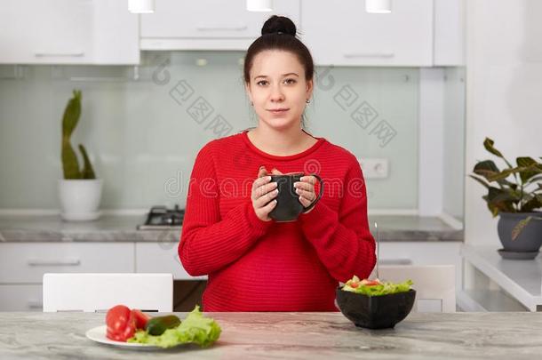 照片关于怀孕的女人饮料热的饮料在的时候晚饭,保存