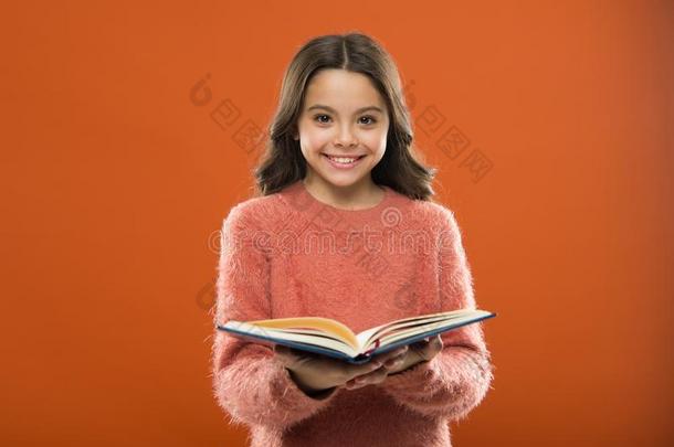 女孩拿住书阅读故事越过桔子背景.小孩享有关于